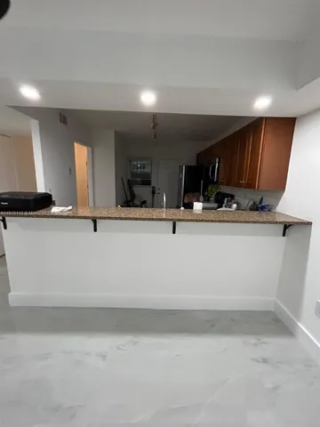 a view of a kitchen with kitchen island a sink stainless steel appliances and cabinets