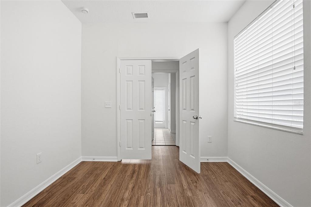 7702 Dragon Fly Loop Gibsonton, FL 33534 - Photo 7 of 42 an empty room with wooden floor and windows