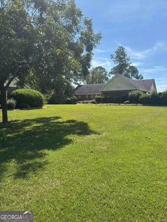 a view of a big yard with table and chairs under an umbrella