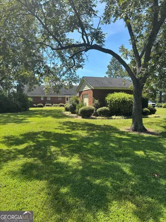 a view of a house with a big yard and large trees
