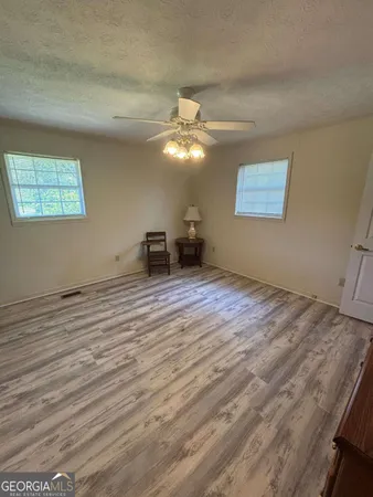 a view of an empty room with window and chandelier fan