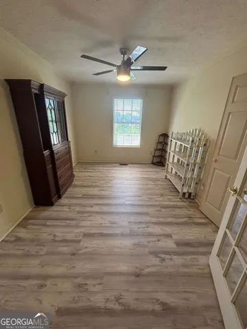 a view of empty room with wooden floor and fan