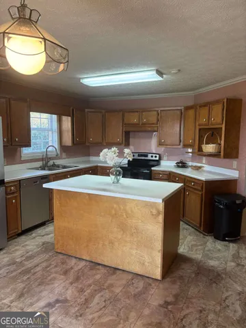 a kitchen with stainless steel appliances granite countertop a stove a sink a refrigerator a center island and a window