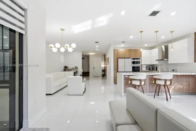 a large white kitchen with a refrigerator a stove a sink a dining table and chairs