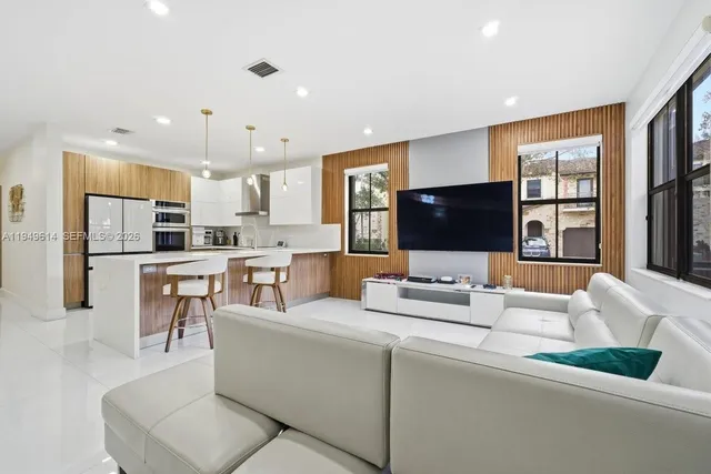 a living room with stainless steel appliances furniture and a flat screen tv