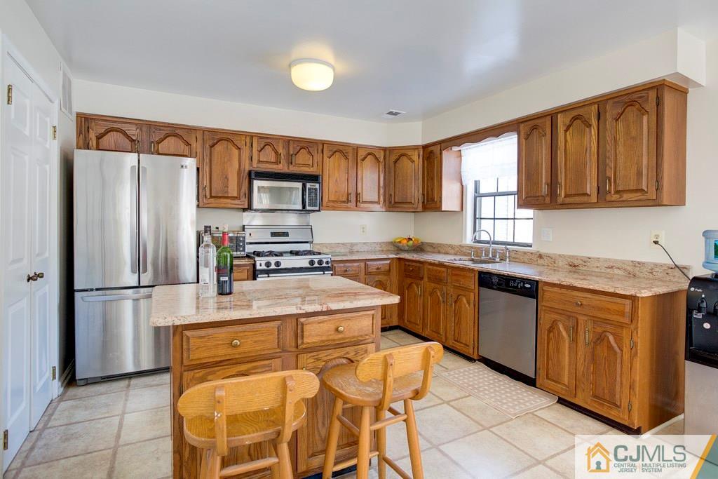 4401 Stonehedge Road, Unit 44 Edison, NJ 08820 - Photo 6 of 24 a kitchen with stainless steel appliances granite countertop a refrigerator a stove a sink and a microwave