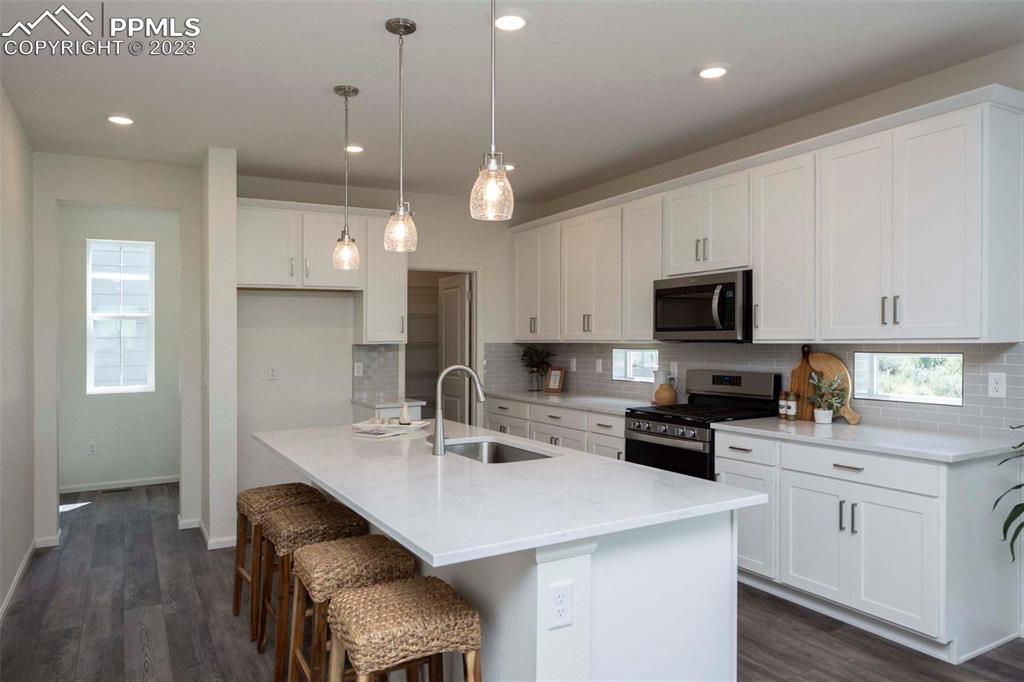 2050 Peachleaf Loop Castle Rock, CO 80108 - Photo 10 of 25 a kitchen with cabinets a sink a stove a microwave a refrigerator and cabinets