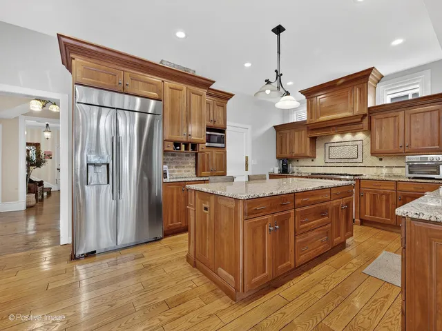 a kitchen with stainless steel appliances granite countertop a refrigerator a oven and a sink with large countertops