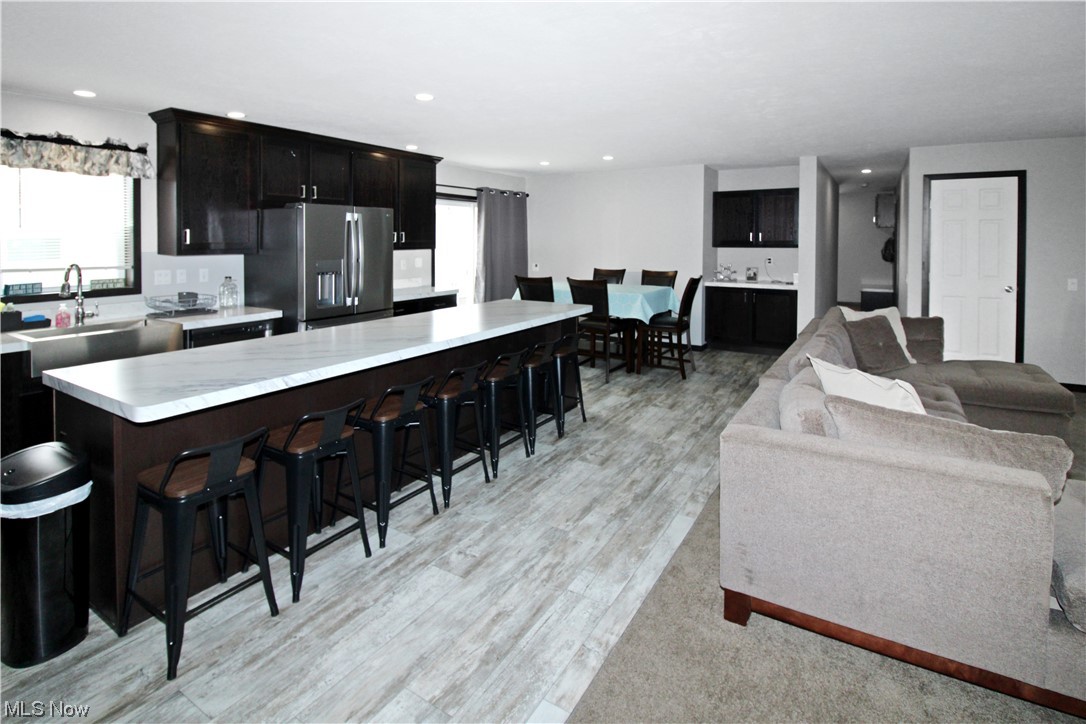 1609 Coldwater Crossing Road Lakeside Marblehead, OH 43440 - Photo 15 of 38 Kitchen with light hardwood / wood-style floors, a kitchen bar, a center island, sink, and stainless steel fridge with ice dispenser