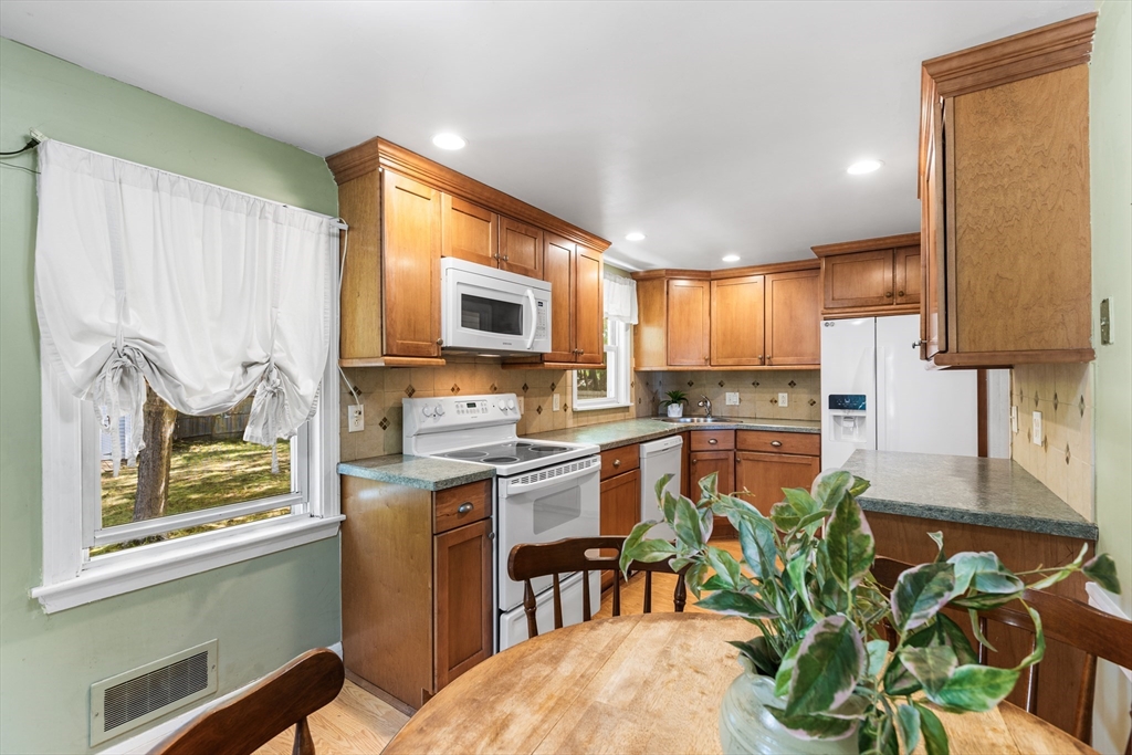 40 Bonad Road Stoneham, MA 02180 - Photo 11 of 38 a open kitchen with stainless steel appliances granite countertop a stove top oven a sink a dining table and chairs with wooden floor