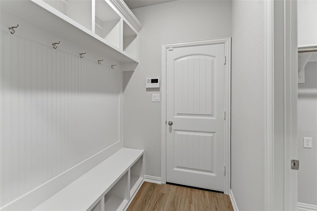 1329 Frio Drive Springtown, TX 76082 - Photo 10 of 25 Dedicated mudroom area featuring a built-in bench with storage cubbies, beadboard paneling, coat hooks, upper shelving, and wood-finish flooring