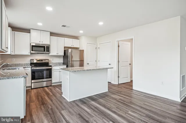 a kitchen with granite countertop white cabinets and stainless steel appliances