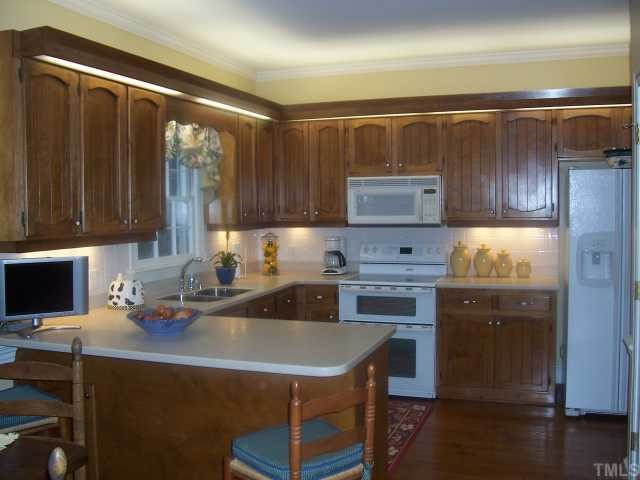 7909 Sutterton Court Raleigh, NC 27615 - Photo 4 of 12 Solid Surface Countertops, Ceramic Backsplash, all appl replaced '01. 9' Smooth Ceil, Chairriail, Crown Molding + Pine Flr. Over & Under Cabinet Lighting. Eat-at Bar. Kitchen