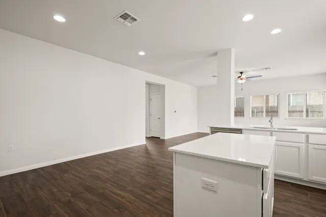 a large white kitchen with wooden floor and sink