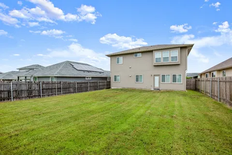 a view of a house with a yard and a large tree
