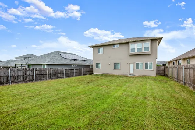 a view of a house with a yard and a large tree