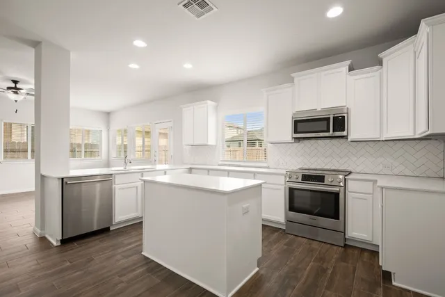 a kitchen with stainless steel appliances granite countertop a stove top oven a sink dishwasher and a refrigerator