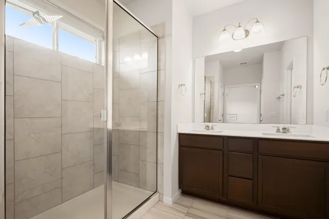 a bathroom with a double vanity sink mirror and shower