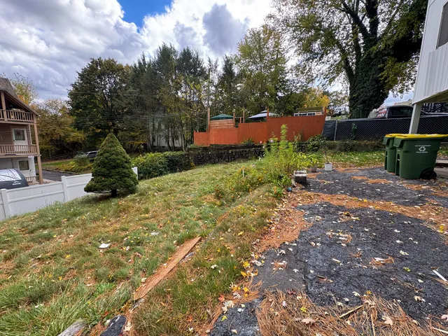 a view of an empty room with wooden floor and fan
