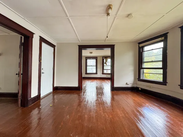an empty room with wooden floor and windows