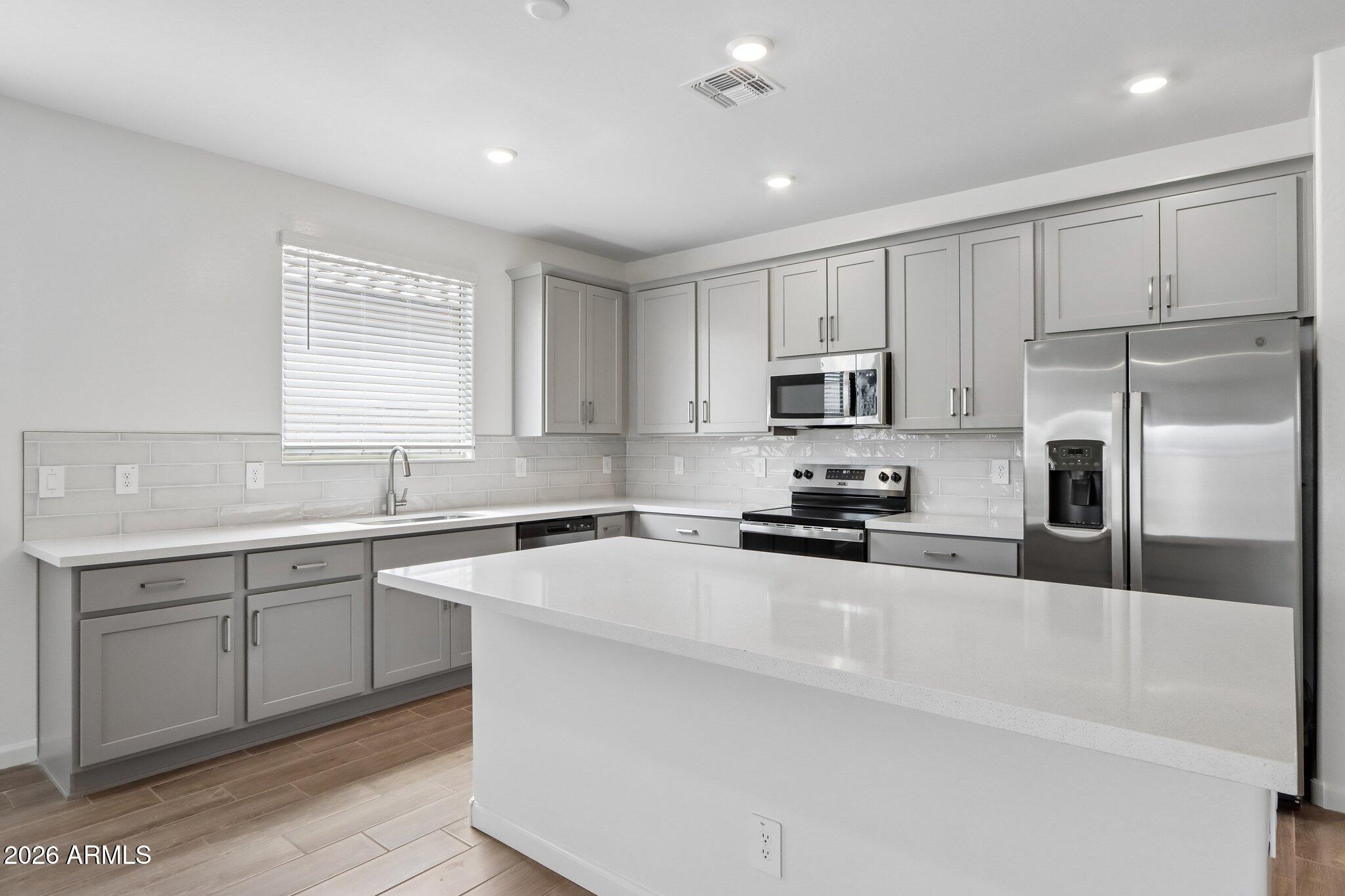 9544 West Gaby Road Tolleson, AZ 85353 - Photo 13 of 43 a kitchen with a sink a microwave a refrigerator and cabinets