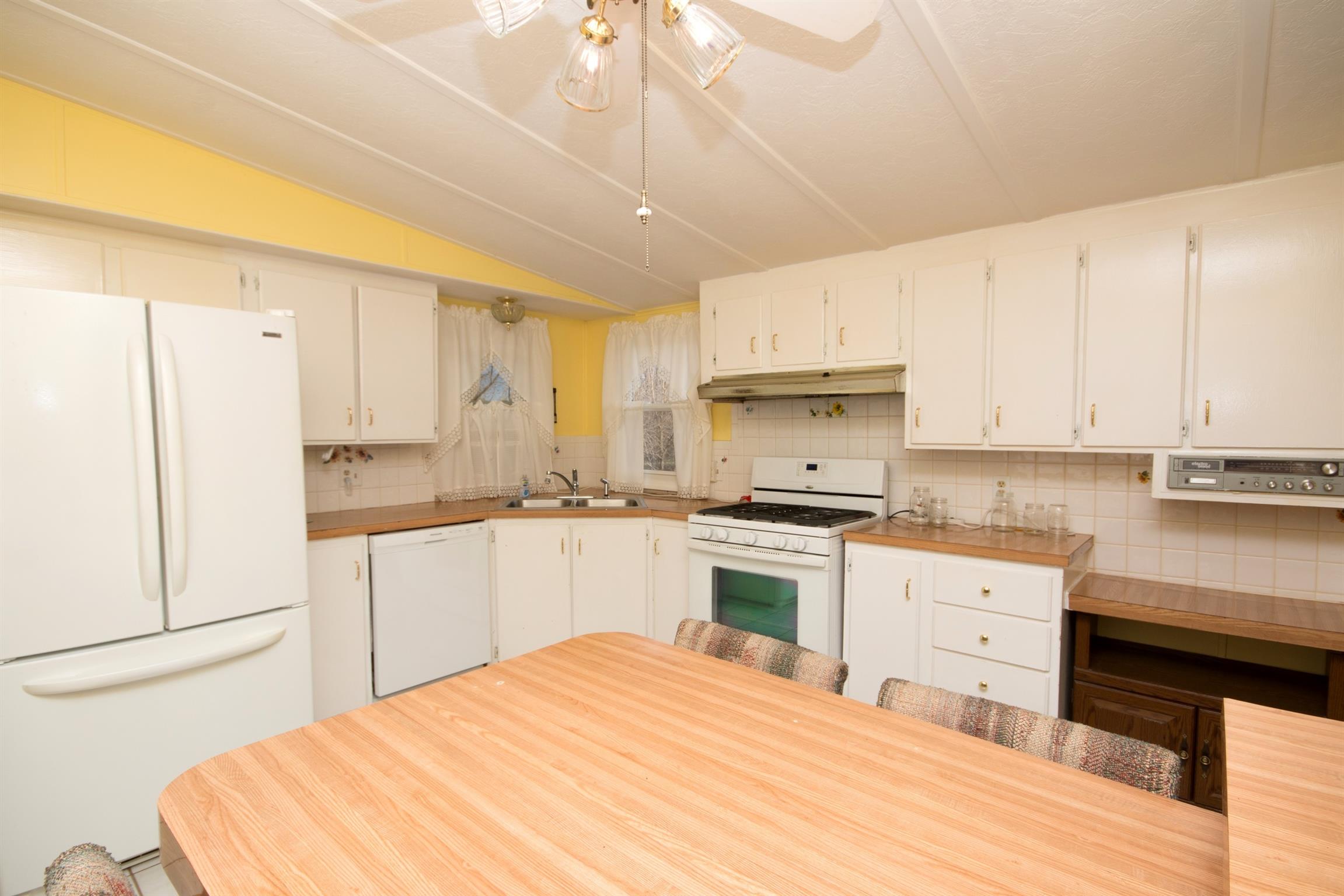 149 Mitchell Road Portland, TN 37148 - Photo 19 of 29 a kitchen with granite countertop a refrigerator a stove a sink dishwasher and white cabinets with wooden floor