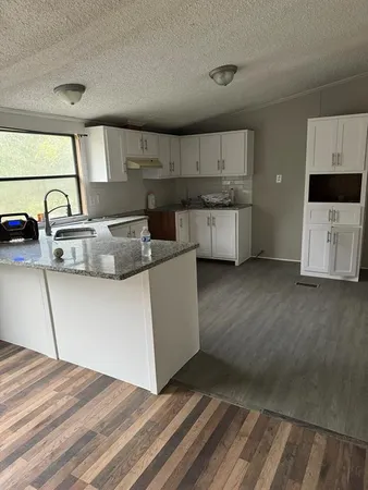 a kitchen with stainless steel appliances granite countertop a sink stove and white cabinets with wooden floor