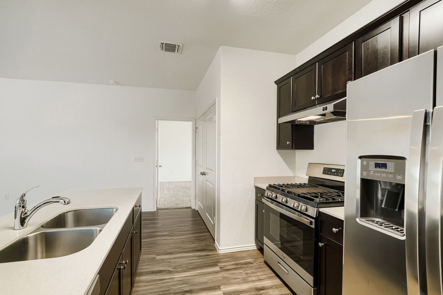 7001 Tonka Lane Austin, TX 78744 - Photo 11 of 30 a kitchen with stainless steel appliances a sink a stove and a refrigerator with wooden floor