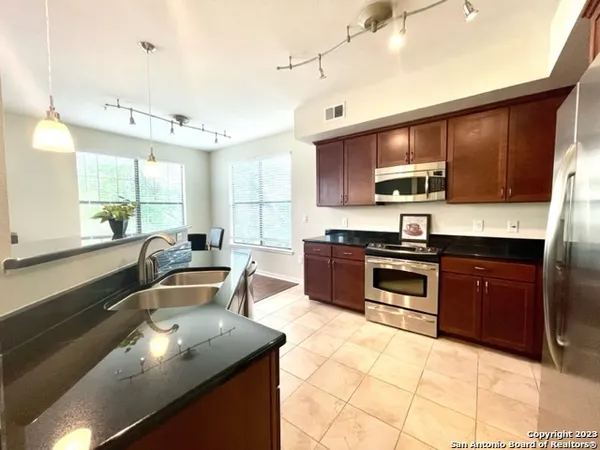 a kitchen with stainless steel appliances granite countertop a sink a stove counter space and cabinets