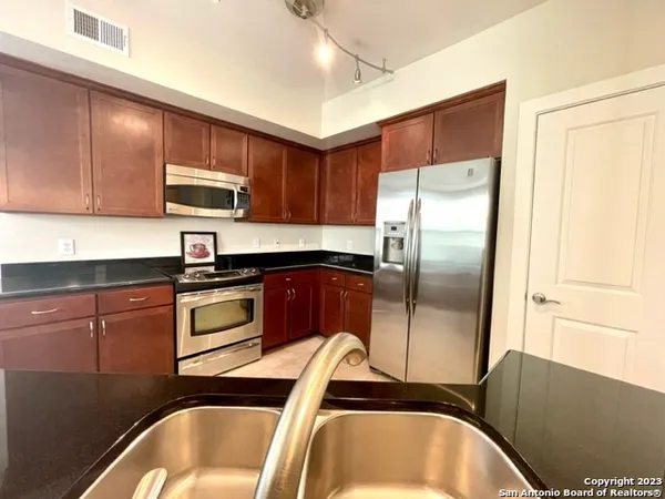 a kitchen with stainless steel appliances granite countertop a sink refrigerator and microwave