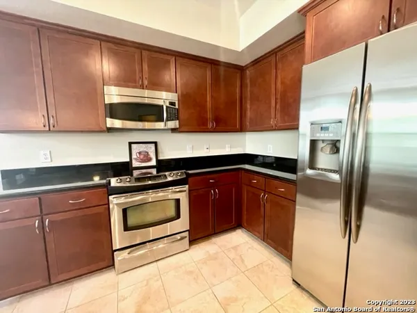 a kitchen with granite countertop a refrigerator and a stove top oven
