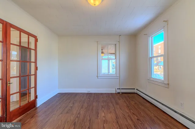 an empty room with wooden floor and windows