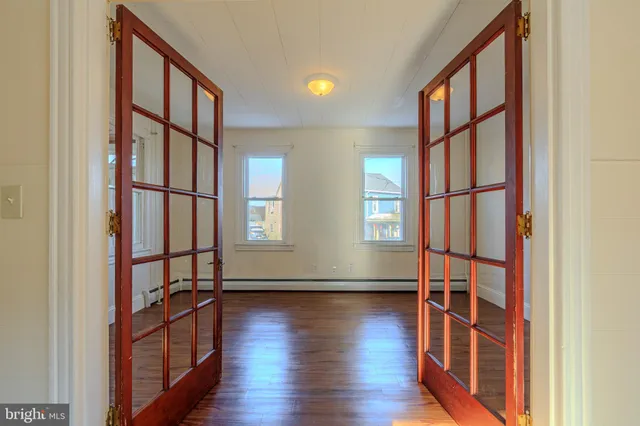 a view of empty room with wooden floor and fan