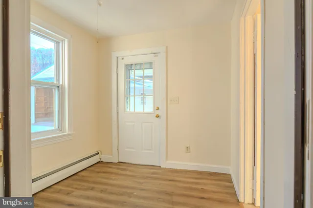 a view of an empty room with wooden floor and a window