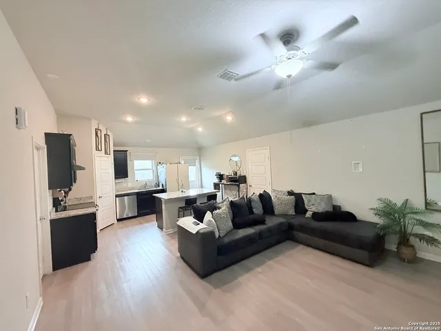 a living room with furniture kitchen area and a flat screen tv