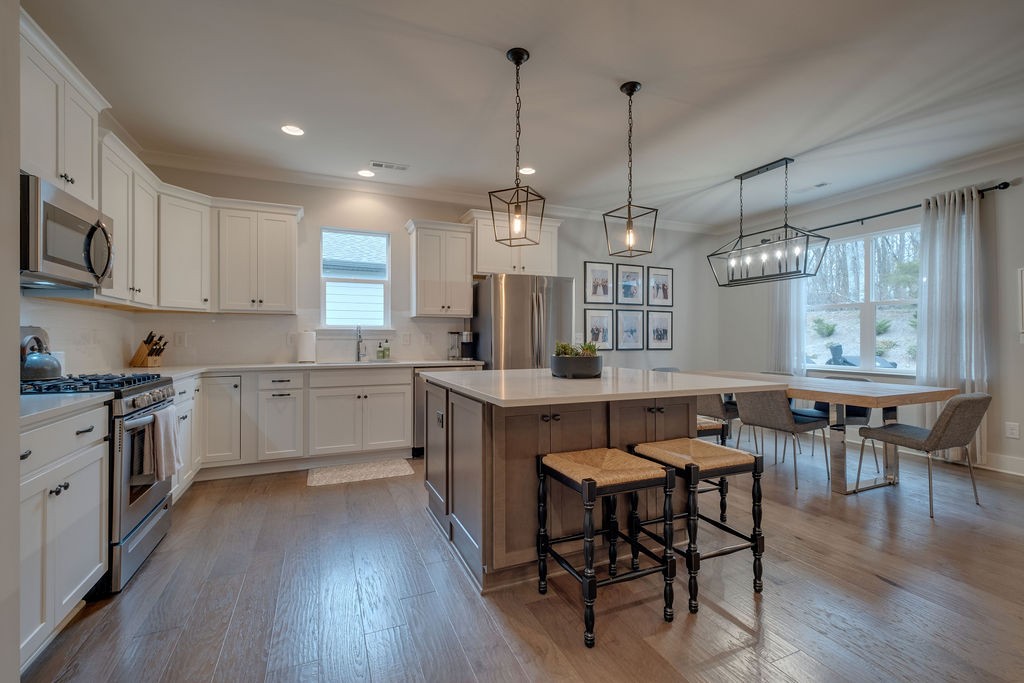 713 Plowson Road Mount Juliet, TN 37122 - Photo 6 of 33 a kitchen with stainless steel appliances granite countertop a stove a refrigerator a kitchen island a dining table and chairs with wooden floor