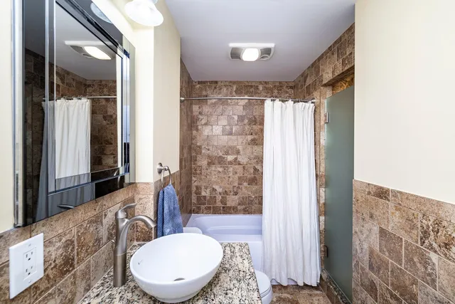 a bathroom with a granite countertop toilet sink and mirror