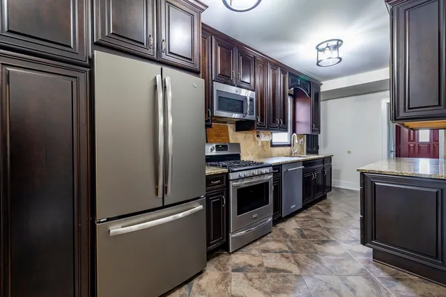 a kitchen with stainless steel appliances granite countertop a refrigerator stove and sink