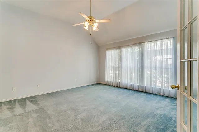 an empty room with windows and chandelier fan