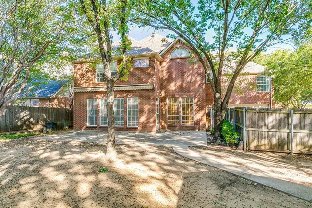 a view of a house with a large tree and wooden fence