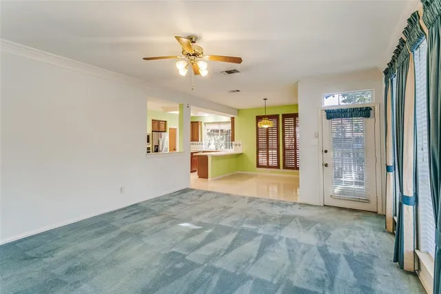 a view of a livingroom with a chandelier fan and windows