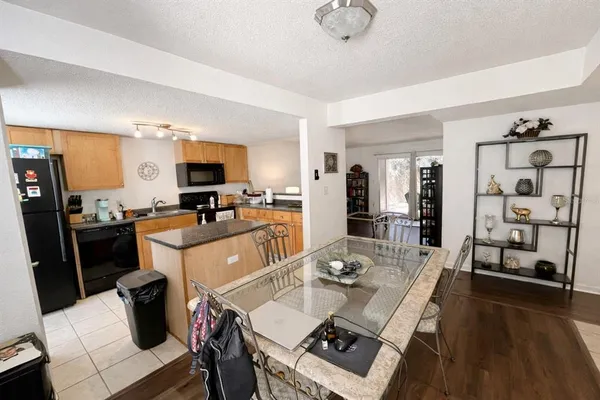 a kitchen with stainless steel appliances granite countertop a refrigerator a stove top oven a sink a dining table and chairs