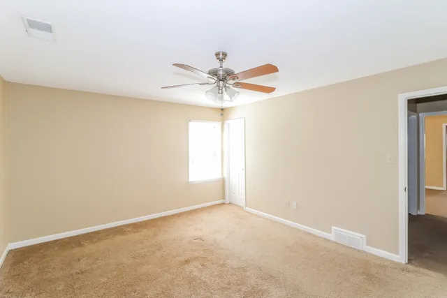 an empty room with a window and a fan