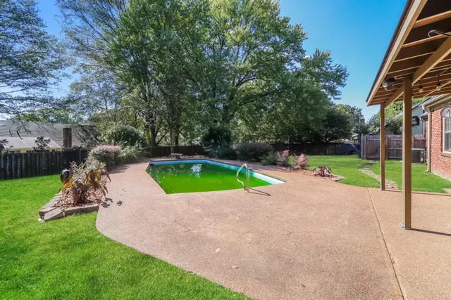 a backyard of a house with wooden fence and large trees
