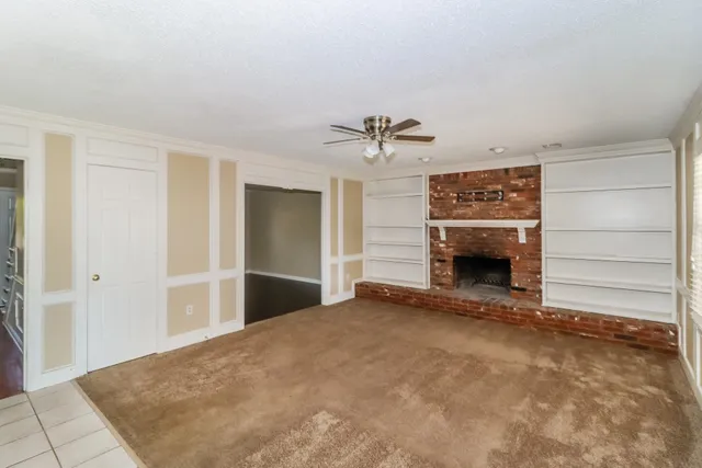 a view of an empty room with a fireplace and a window