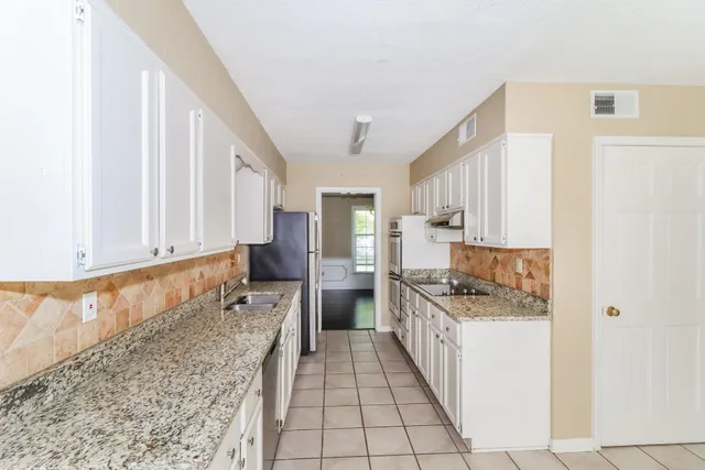 a large kitchen with granite countertop a sink and a stove