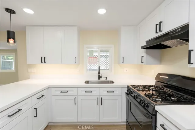a kitchen with granite countertop a sink a stove and wooden cabinets