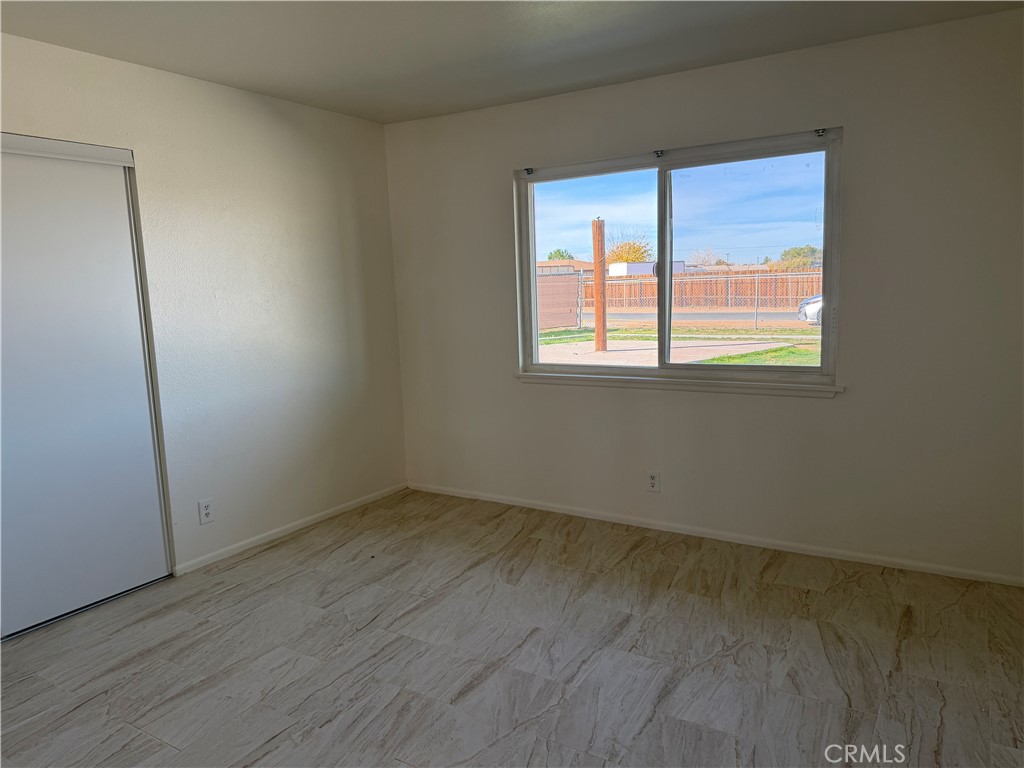 15225 Ramona Road Apple Valley, CA 92307 - Photo 2 of 8 an empty room with wooden floor and windows