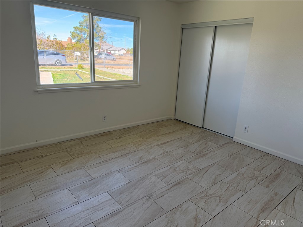 15225 Ramona Road Apple Valley, CA 92307 - Photo 5 of 8 an empty room with wooden floor and windows