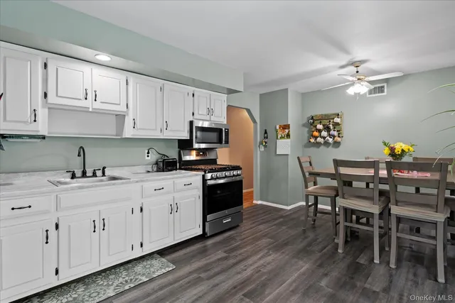 a kitchen with stainless steel appliances granite countertop a white cabinets and wooden floor